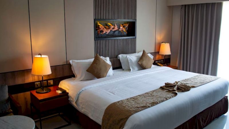 A hotel room with a large bed, two nightstands, lamps, and a flat-screen TV mounted on the wall.
