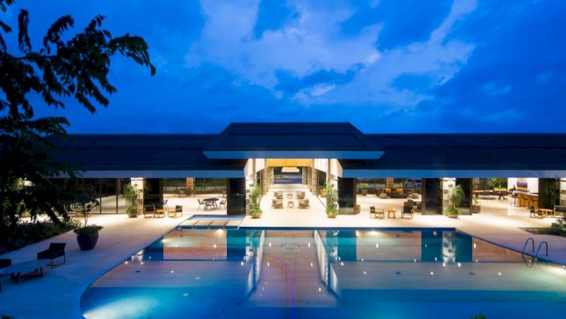A large hotel exterior with a pool at night