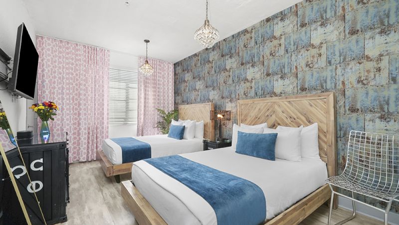 A hotel room with two beds, blue and white bedding, and a chandelier.