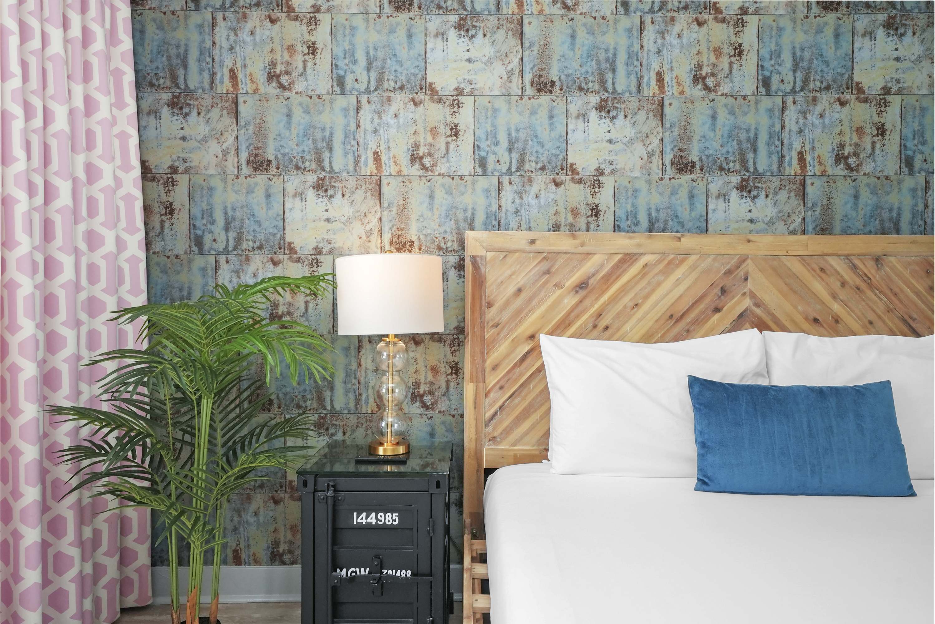 A guest room with a wooden headboard, white bedding, and a blue accent pillow.