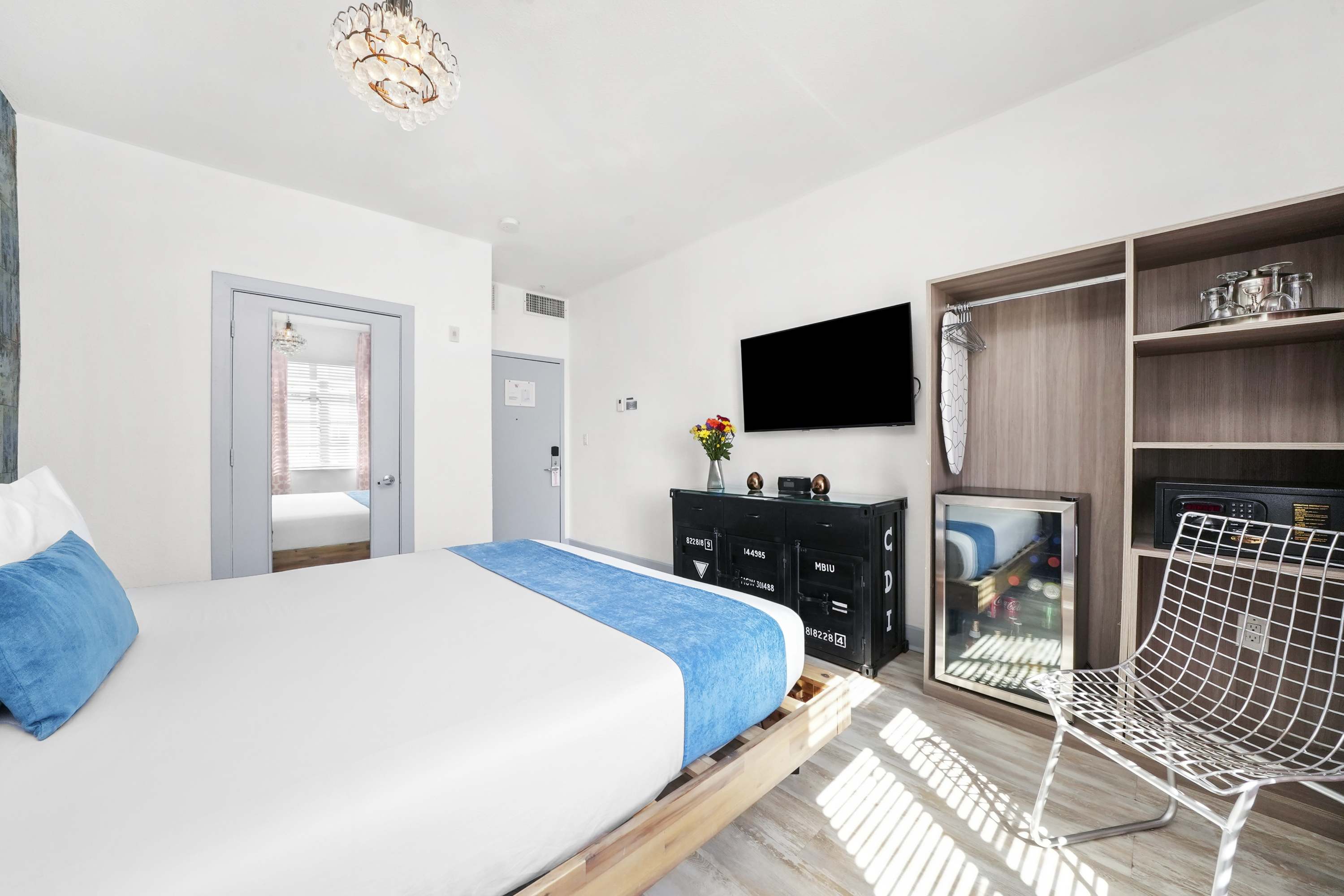 A hotel room with a bed, TV, chair, closet, and dresser.