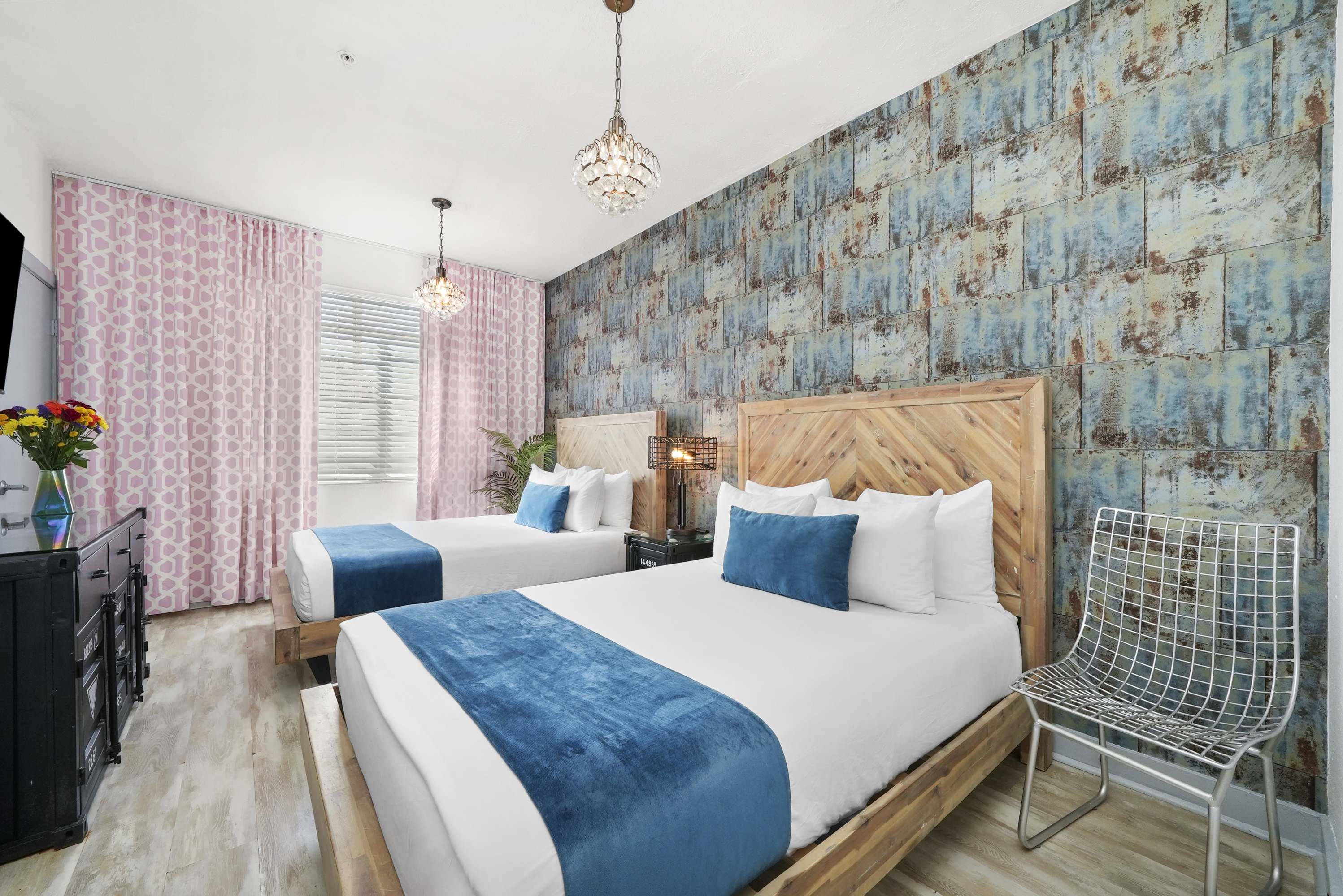A hotel room with two beds, a wooden headboard, and blue accents.
