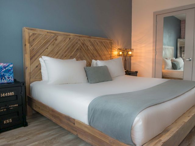 A hotel room with a large bed, wooden furniture, and a mirror on the wall.