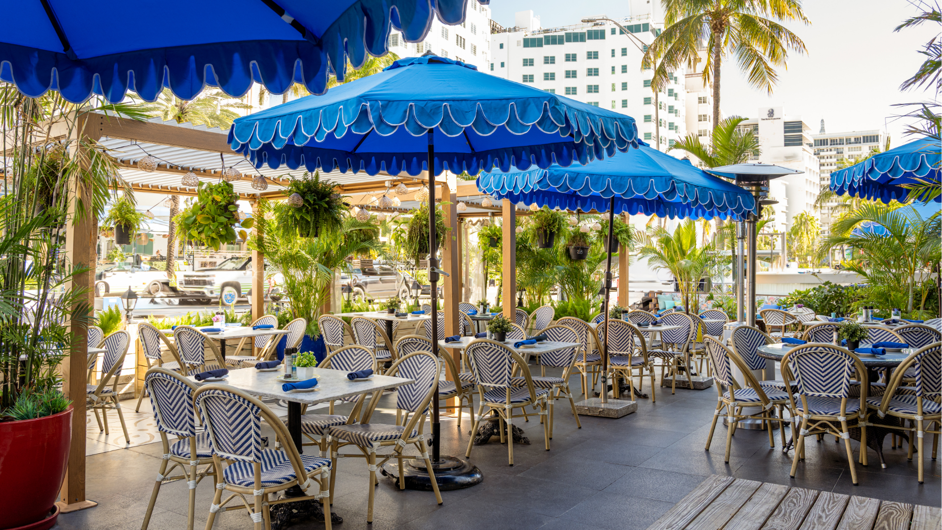 An outdoor dining area with blue umbrellas and tables set for guests.