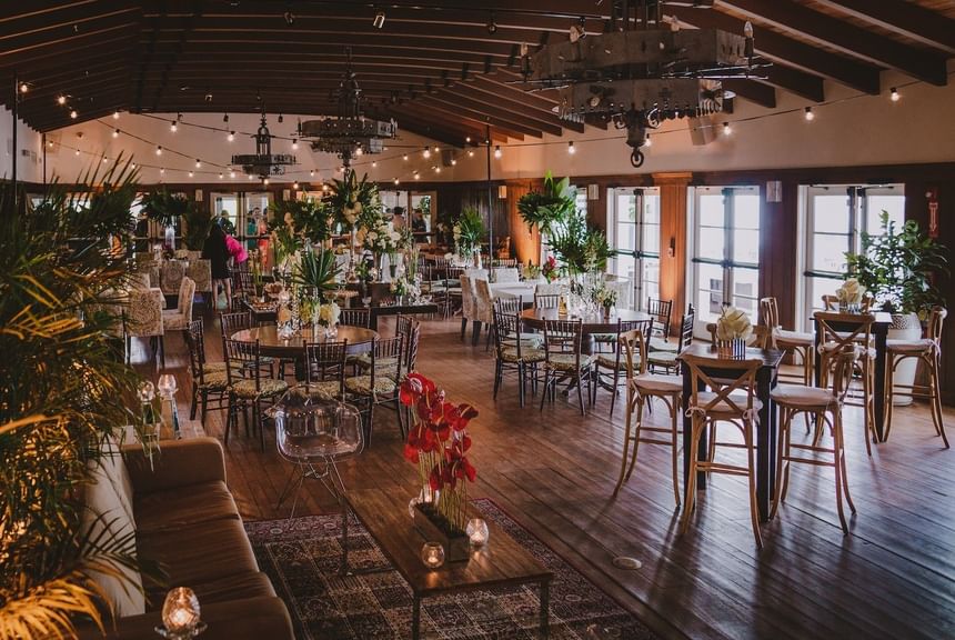 A large dining room with round tables, chairs, and floral arrangements.